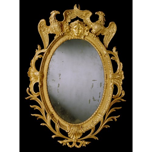 A GEORGE II CARVED GILTWOOD OVAL MIRROR